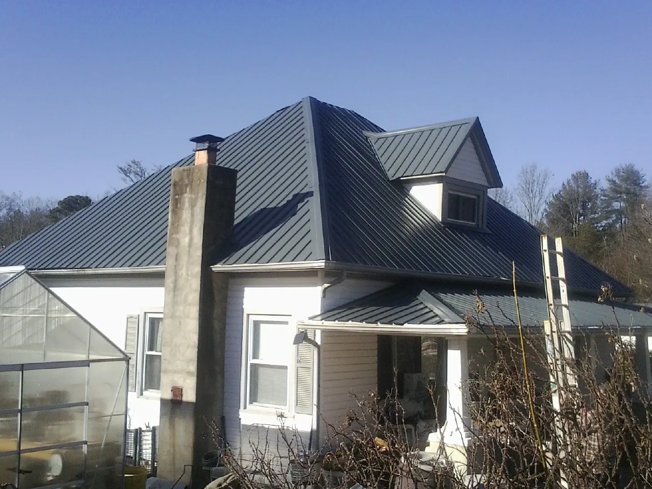 Dark blue standing seam metal roof on a white farmhouse with dormer — Slate & Tile Roof Repair by Roofing Brothers in Eagan