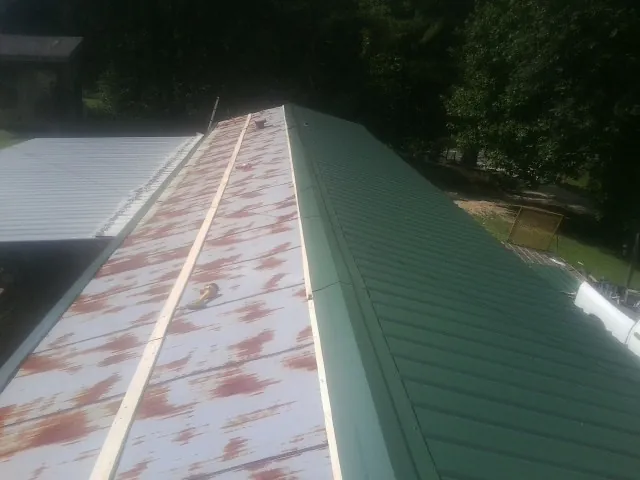 Old rusted panels beside newly installed green metal roofing — Wind Damage Roof Repair by Roofing Brothers in Eagan