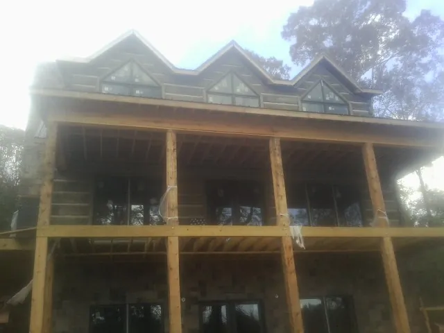 Dormers and porch framing on a large log home under construction — Roof Coating work by our crew in Eagan
