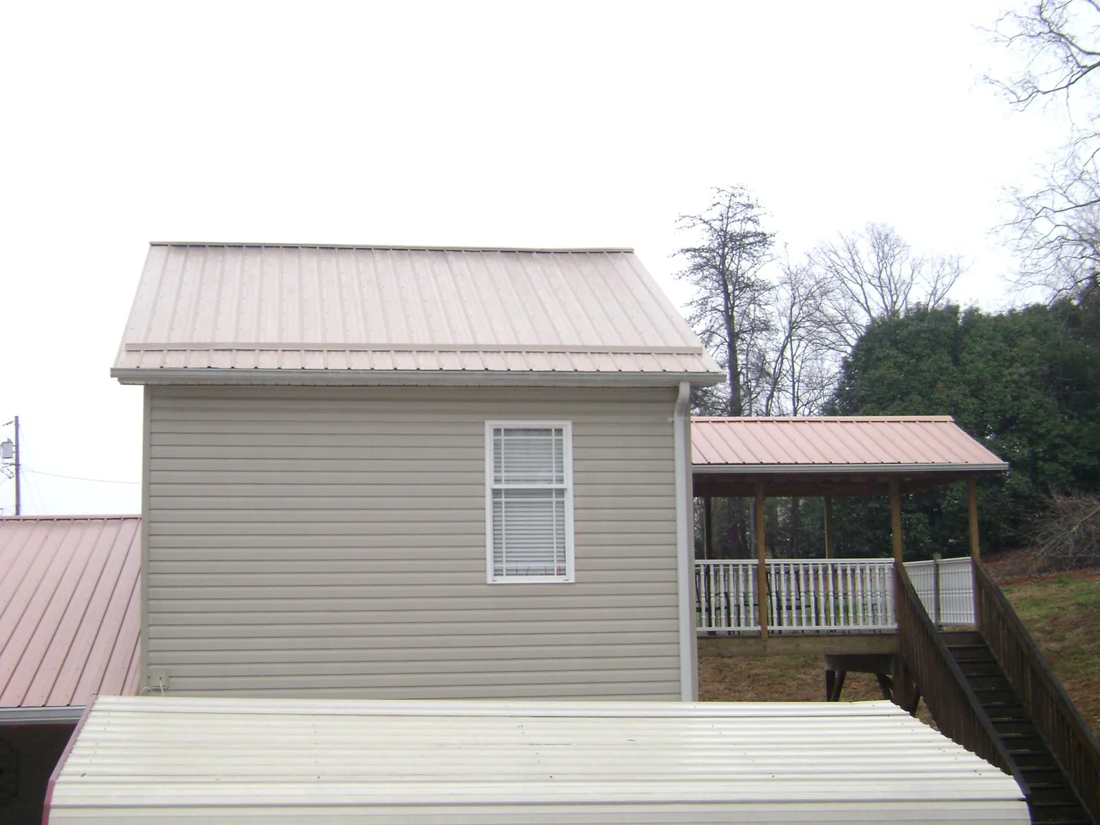 Tan metal roofs on a two story addition and attached porch, from a Roof Replacement job in Eagan