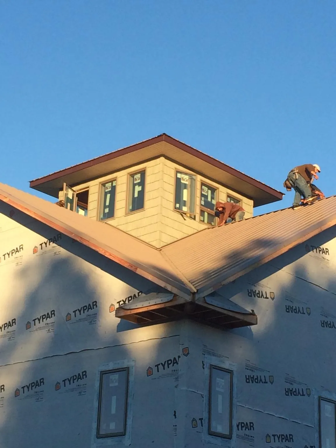 Roofers working around a rooftop cupola on a new metal roof at sunset — Roof Waterproofing in Eagan by Roofing Brothers